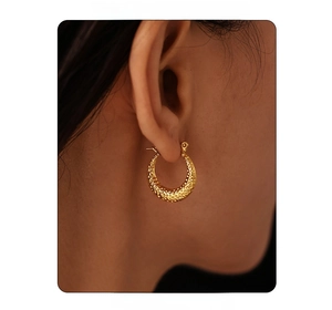 Close-up of model wearing gold C-shaped hoop earrings with retro hammered texture