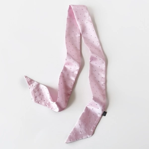 Detailansicht eines rosa Satin-Schals mit silbernen Nieten und glatter Textur