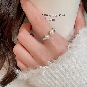 Close-up of adjustable silver ring with two white pearls on a model finger