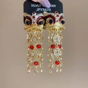 Détail de boucles d'oreilles danse du lion avec glands dorés et émail rouge brillant