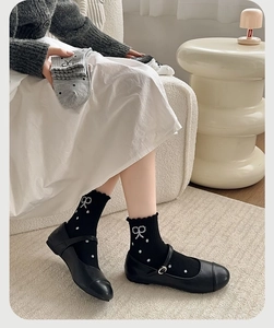 Detail of knit socks showing ruffled cuffs with polka dots and bow embroidery accents