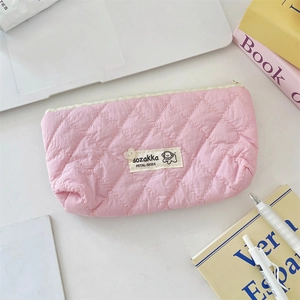 Vue à plat d'une trousse de maquillage rose matelassée avec écusson de chien mignon