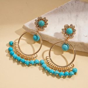 Detail of bohemian gold hoop earrings with turquoise beads on white stone props