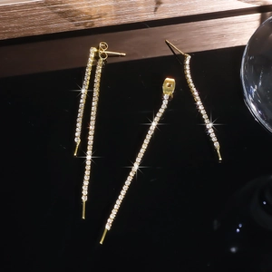 Macro shot of elegant long tassel earrings with sparkling rhinestones in gold finish