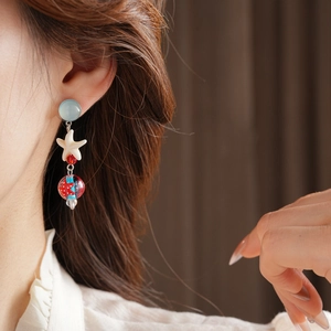Close-up of starfish drop earrings with blue and red beads for a stylish seaside look