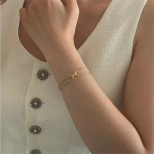 Macro shot of minimalist gold double-layered bracelet with a central twisted knot design