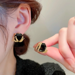 Detail of elegant black gemstone earrings with textured gold coral-like metal framing