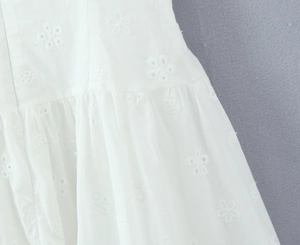 Close-up of intricate white floral embroidery and delicate eyelet details on cotton dress