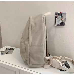Side view detail of khaki canvas backpack showing side pocket and durable fabric texture