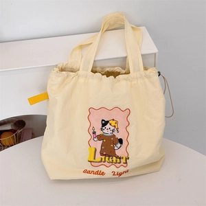 Detail of canvas tote bag with drawstring featuring cute cartoon cat and candle illustration