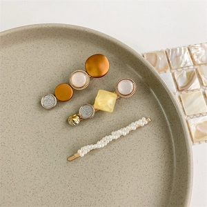 Detailed view of pearl and gold hair clips arranged on a beige ceramic jewelry plate