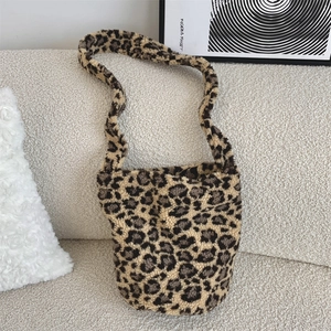 Close-up of leopard print faux fur bucket bag placed on a cozy white boucle sofa