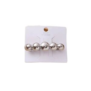 Silver spring hair clip featuring five polished metallic spheres on display card