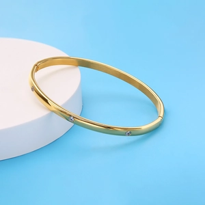 Golden titanium steel bangle with inlaid zircons and screw motifs on geometric stand