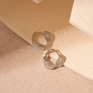 Detailed close-up of silver twisted geometric hoop earrings with textured metal finish