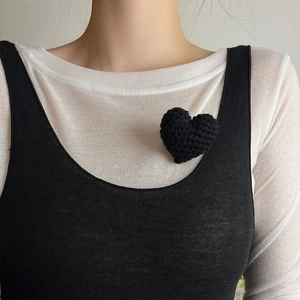 Handmade knitted heart brooch in black wool on a vest, elegant minimalist accessory
