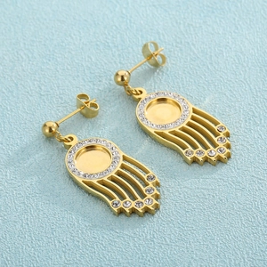 Élégantes boucles d'oreilles dorées avec cristaux scintillants sur fond bleu clair