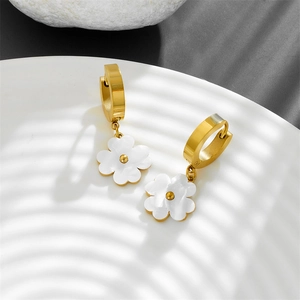Detail of gold titanium steel hoop earrings with white clover charms on a white tray