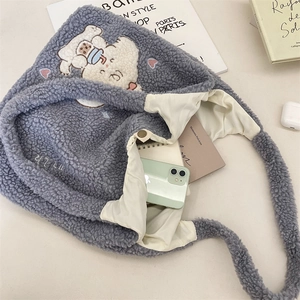 Détail de la broderie de chien mignon sur un sac cabas en peluche grise avec rangement