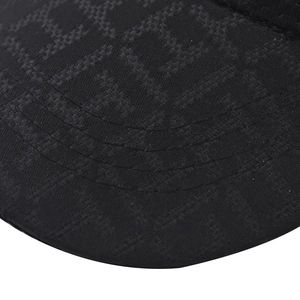 Macro detail of black baseball cap brim with jacquard pattern and reinforced four-row stitching