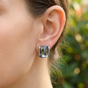 Detail of square smoke gray glass earring with polished silver setting on ear