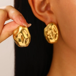 Detail of chunky gold irregular lava-style earrings showing texture and high-shine finish