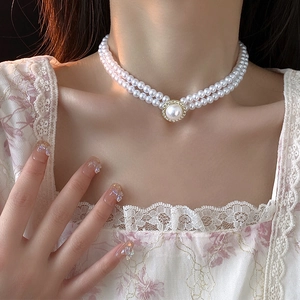 Détail d'un élégant collier de perles à double rang avec pendentif strass brillant