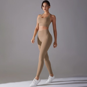 Detail of cross-back sports bra and high-waist yoga pants in light khaki stretch fabric