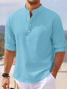 Close-up of light blue waffle texture polo shirt with white buttons and rolled sleeves