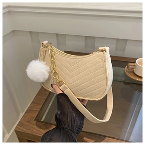 Détail du sac sous le bras en feutre beige avec motif en V et pompon en fourrure blanc