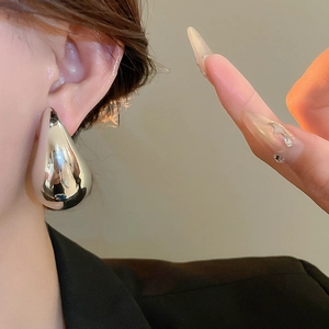 Close-up of a silver teardrop earring with a high-polished mirror finish on a model