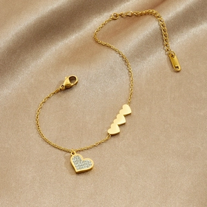 Polished gold heart charm bracelet with sparkling crystals on champagne silk background