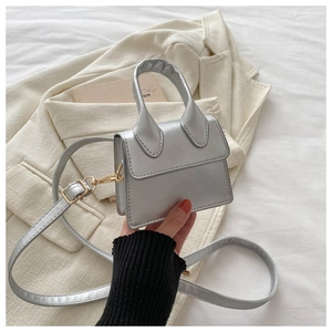 Nahaufnahme einer silbernen Mini-PU-Tasche mit goldenen Beschlägen und Gurt