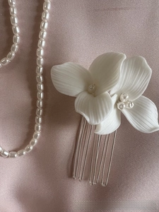 Close-up of white ceramic flower hair comb with freshwater pearl and silver teeth