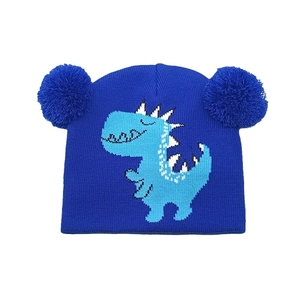 Dettaglio del cappello in maglia blu per bambini con pompon e ricamo di dinosauro