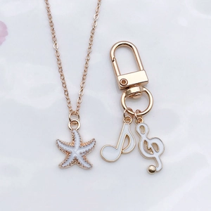 Detail of white enamel musical note and starfish charms with golden alloy finish