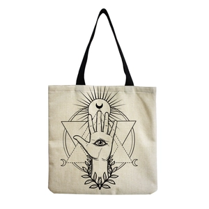 Close-up of beige canvas tote bag featuring black mystic eye and sun geometric prints