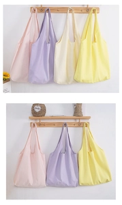 Detail showing various pastel macaron colors of canvas tote bags hanging on wooden hooks