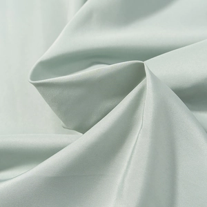 Detailed macro shot of mint green pleated fabric with a silky satin finish and elegant drape