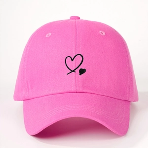 Close-up of black heart embroidery on a bright pink cotton baseball cap with fine stitching