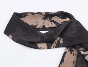 Detail of soft chiffon scarf featuring black and khaki abstract botanical silhouettes