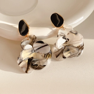 Detailed shot of resin flower earrings with marble texture on a white ceramic plate