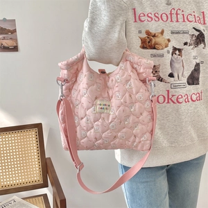 Close-up of pink quilted crossbody bag featuring cute cartoon rabbit prints and woven label