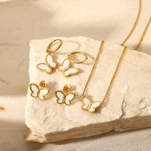 Macro detail of 18K gold plated butterfly jewelry set on natural stone background