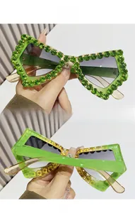 Detail view of butterfly sunglasses with green rhinestones and deep gray lenses