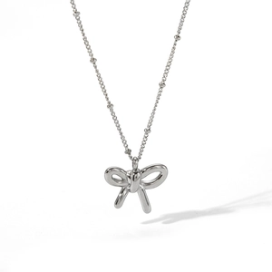 Detailed view of silver bow-shaped necklace with beaded chain on a white background