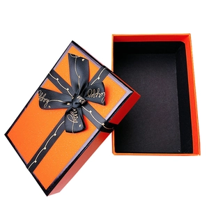 Elegant orange rectangular gift box with black ribbon bow and gold happy lettering