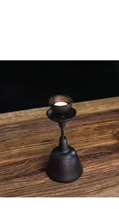 Detail view of a vintage cast iron candle holder with a rustic texture and tea light candle