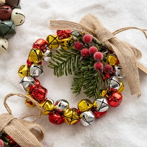 Christmas bell wreath with red berries, pine needles and burlap bow on snow background