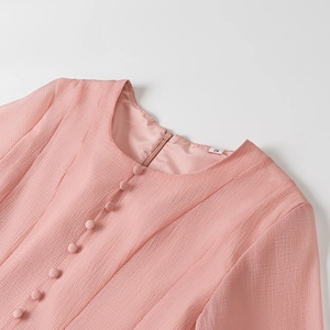 Detail of pink chiffon dress neckline with fabric-covered buttons and round neck